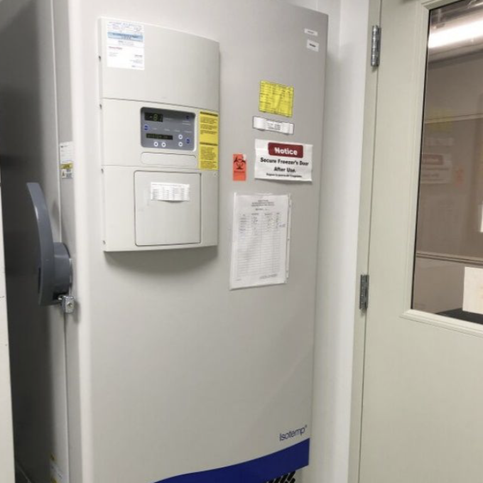 An image of a gray freezer in a small lab room.