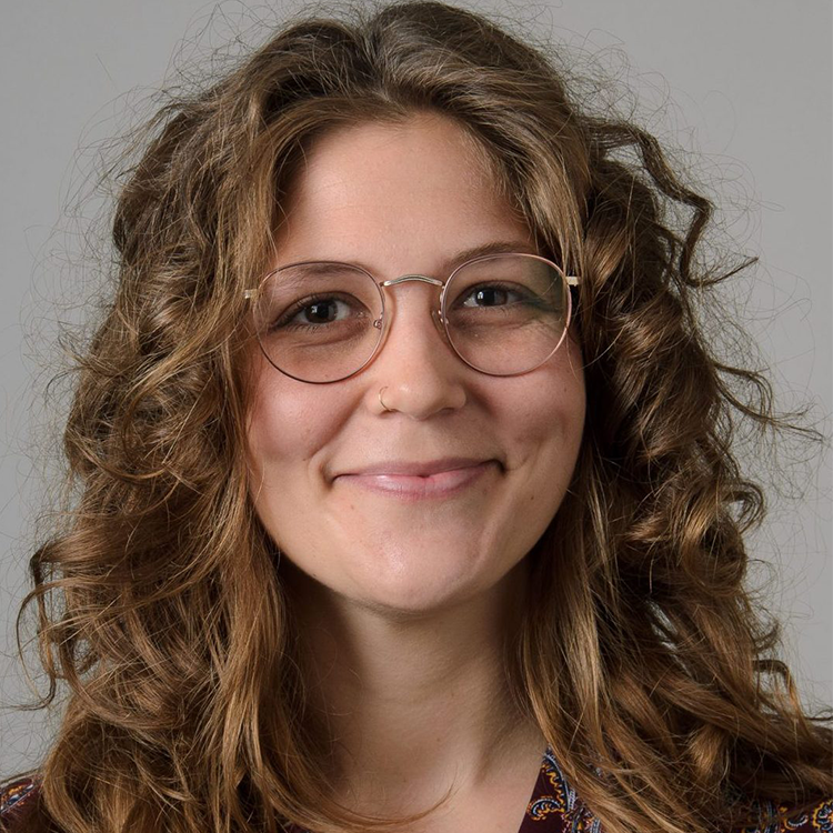 A headshot of Meredith Kuzel against a gray background.