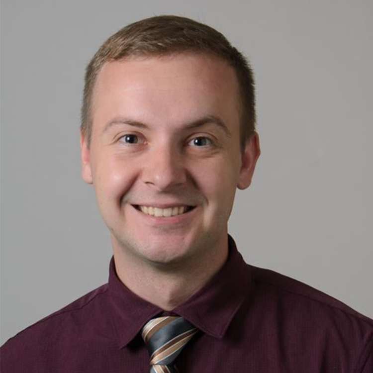 A headshot of Stephen Wetherell against a gray background.